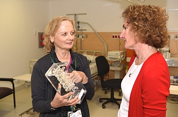 Clinician standing in front of patient with back bone replica in her hand